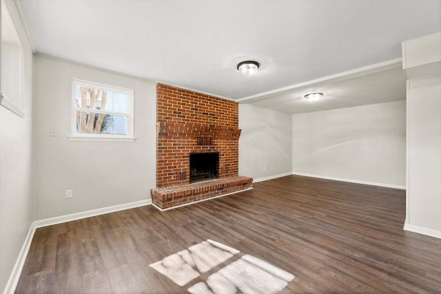 unfurnished living room featuring a brick fireplace and dark hardwood / wood-style floors