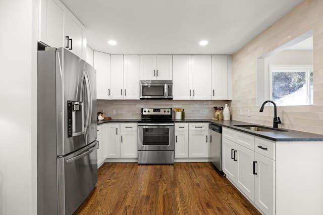 kitchen featuring sink, white cabinets, backsplash, stainless steel appliances, and dark wood-type flooring