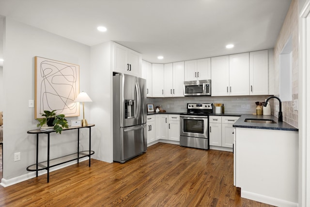 kitchen featuring sink, white cabinetry, dark hardwood / wood-style flooring, stainless steel appliances, and backsplash