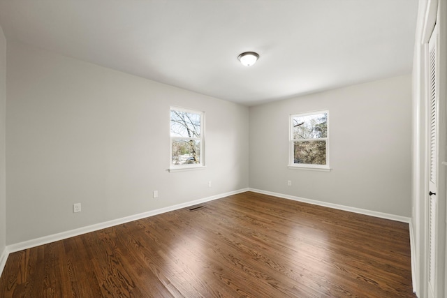 unfurnished bedroom with multiple windows and dark wood-type flooring