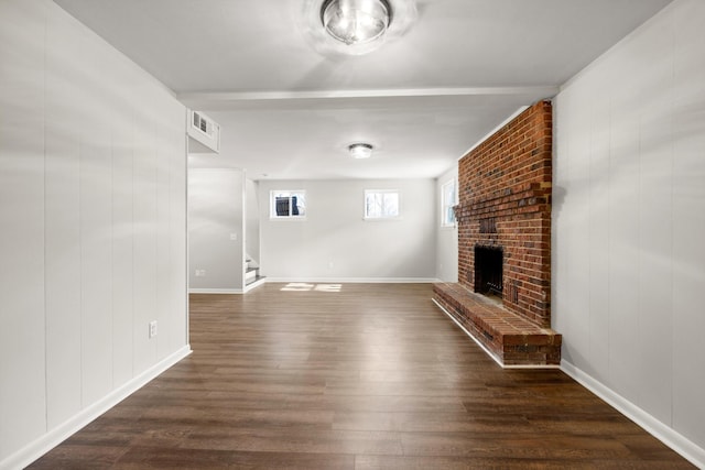 unfurnished living room with a brick fireplace and dark hardwood / wood-style floors