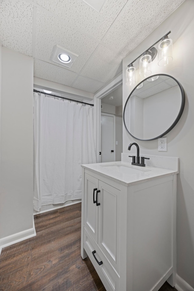 bathroom with hardwood / wood-style flooring, vanity, and a paneled ceiling