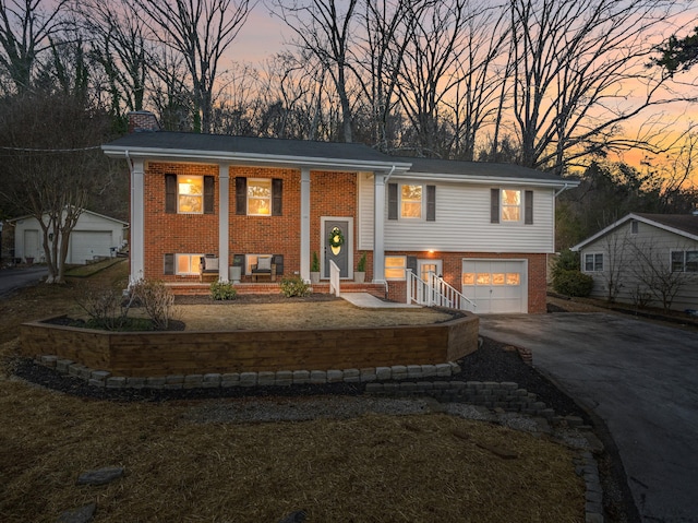 raised ranch with a porch, a garage, and a yard