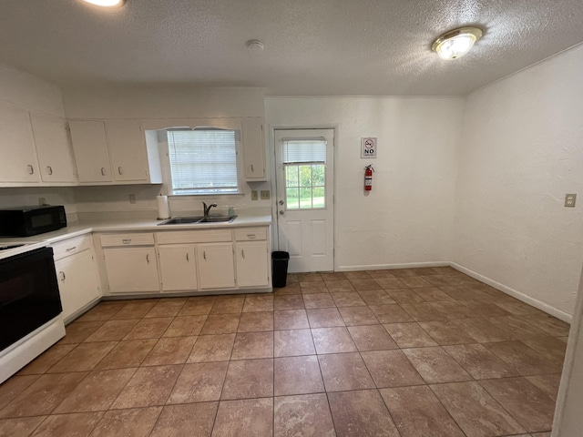 kitchen featuring sink, range, white cabinetry, a textured ceiling, and light tile patterned flooring