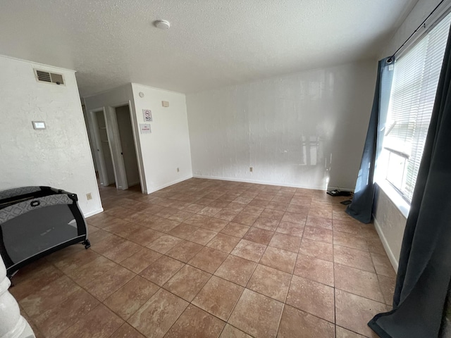 tiled spare room featuring a textured ceiling