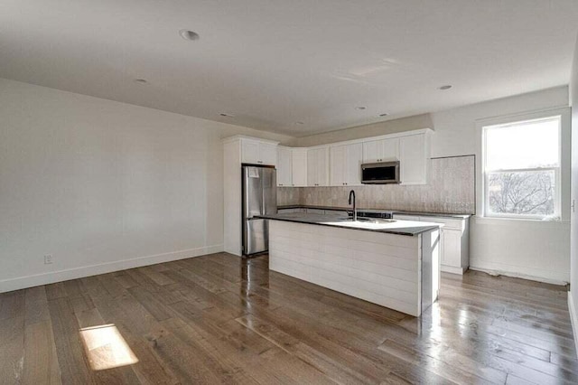 kitchen featuring white cabinetry, dark hardwood / wood-style flooring, decorative backsplash, a kitchen island with sink, and stainless steel appliances