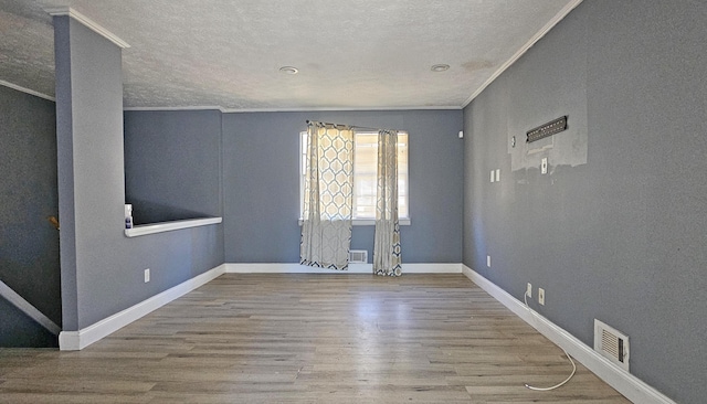 spare room with hardwood / wood-style flooring, ornamental molding, and a textured ceiling