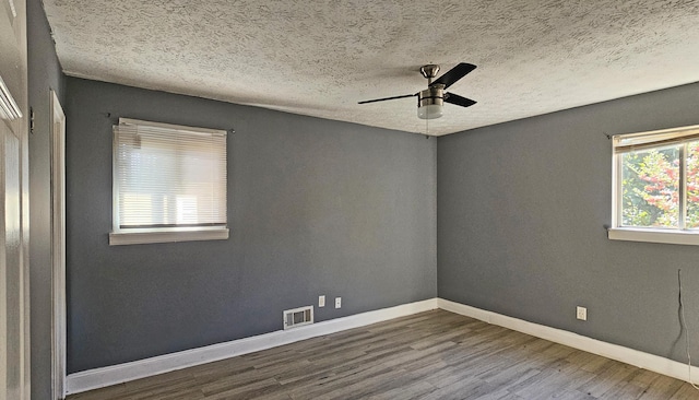 empty room with ceiling fan, wood-type flooring, and a textured ceiling