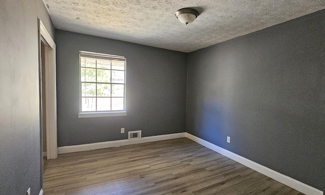 unfurnished room with hardwood / wood-style flooring and a textured ceiling