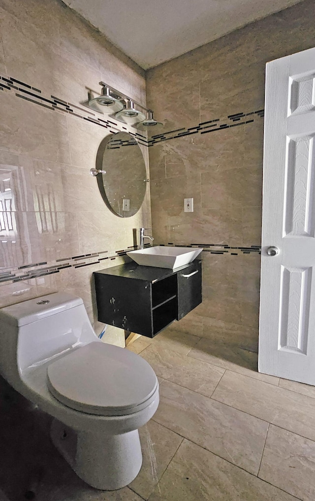 bathroom featuring tile patterned floors, vanity, toilet, and tile walls