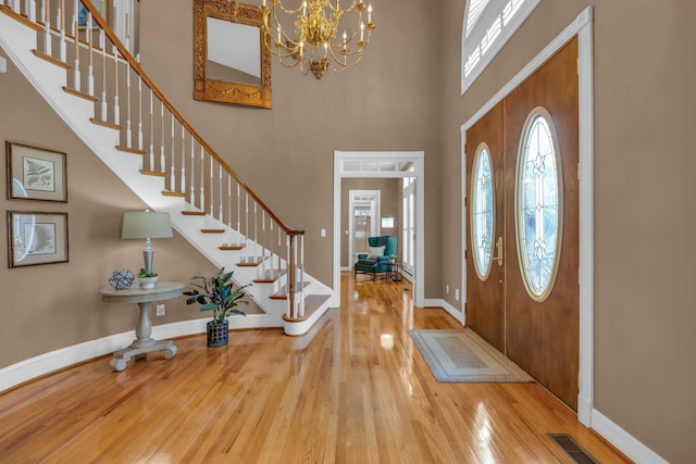 foyer featuring hardwood / wood-style flooring, an inviting chandelier, and a high ceiling