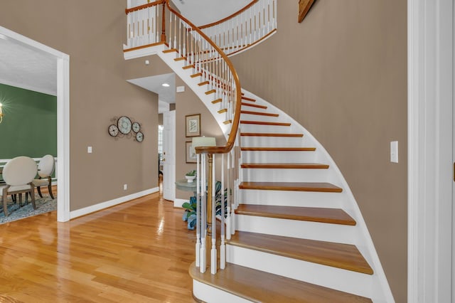 staircase with hardwood / wood-style flooring and a high ceiling