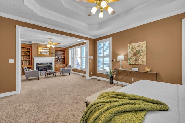 bedroom featuring crown molding, light carpet, a raised ceiling, ceiling fan, and a fireplace