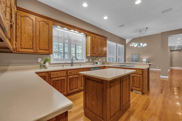 kitchen featuring sink, decorative light fixtures, a center island, kitchen peninsula, and light hardwood / wood-style floors