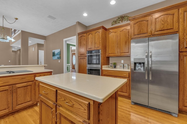 kitchen featuring light hardwood / wood-style flooring, hanging light fixtures, stainless steel appliances, a center island, and a notable chandelier