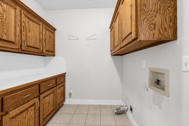 clothes washing area featuring light tile patterned flooring, cabinets, hookup for a washing machine, and a textured ceiling