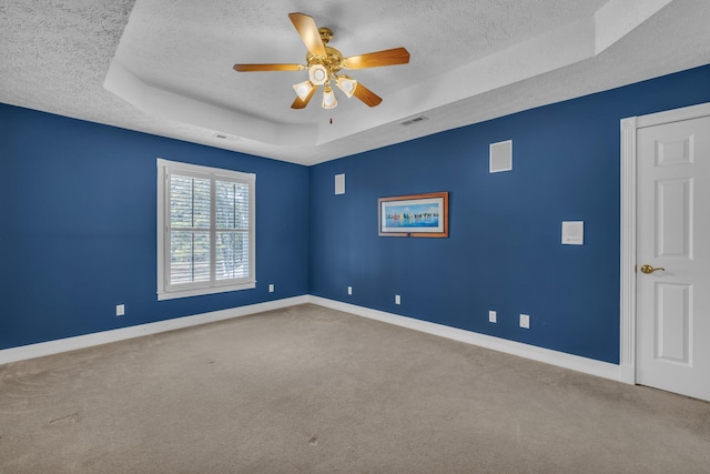 carpeted spare room with a raised ceiling, a textured ceiling, and ceiling fan