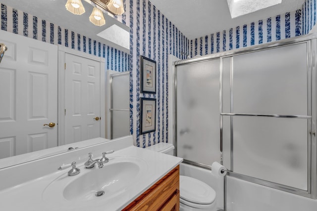 full bathroom with vanity, toilet, a skylight, and combined bath / shower with glass door