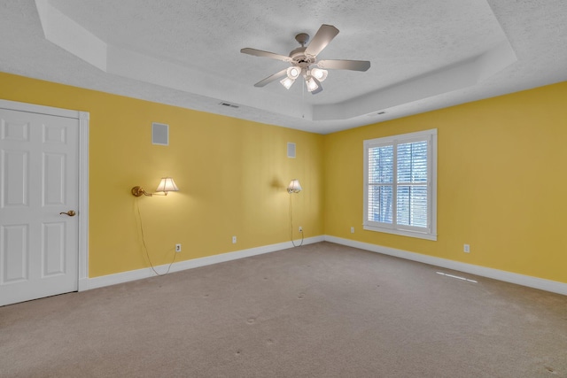 empty room with ceiling fan, a tray ceiling, carpet, and a textured ceiling