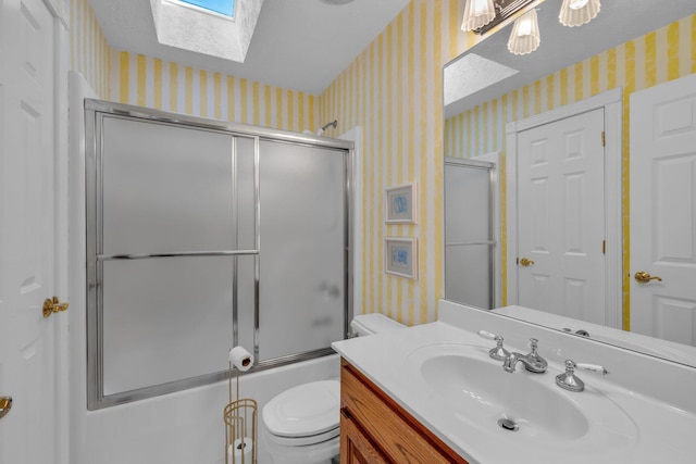 full bathroom with toilet, shower / bath combination with glass door, a skylight, a textured ceiling, and vanity