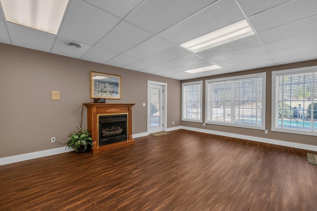 unfurnished living room featuring a paneled ceiling and dark hardwood / wood-style flooring