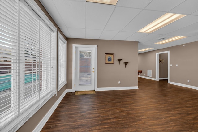 interior space with dark hardwood / wood-style floors and a drop ceiling