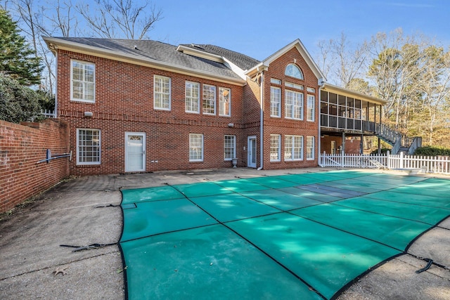 back of house with a sunroom, a patio, and a covered pool