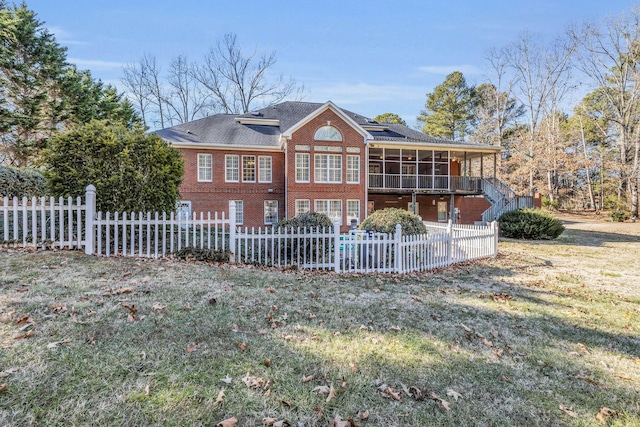 rear view of house featuring a sunroom and a lawn