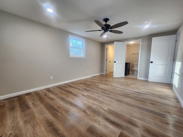 unfurnished bedroom featuring ensuite bath, light hardwood / wood-style floors, and ceiling fan