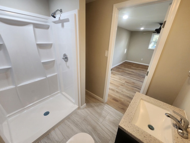 bathroom featuring walk in shower, ceiling fan, and vanity