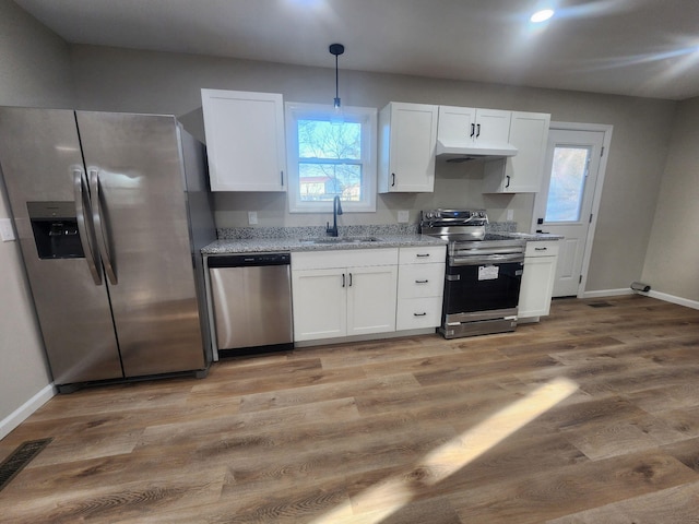 kitchen featuring stainless steel appliances, sink, white cabinets, and decorative light fixtures