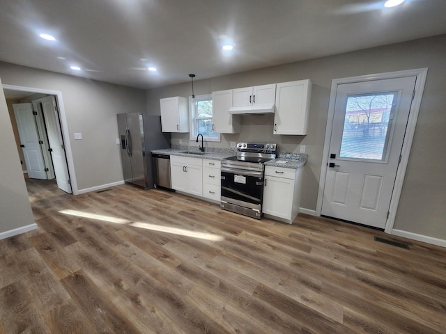 kitchen with stainless steel appliances, white cabinetry, sink, and decorative light fixtures