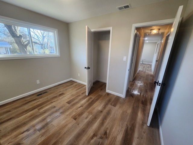 unfurnished bedroom with baseboards, visible vents, and wood finished floors