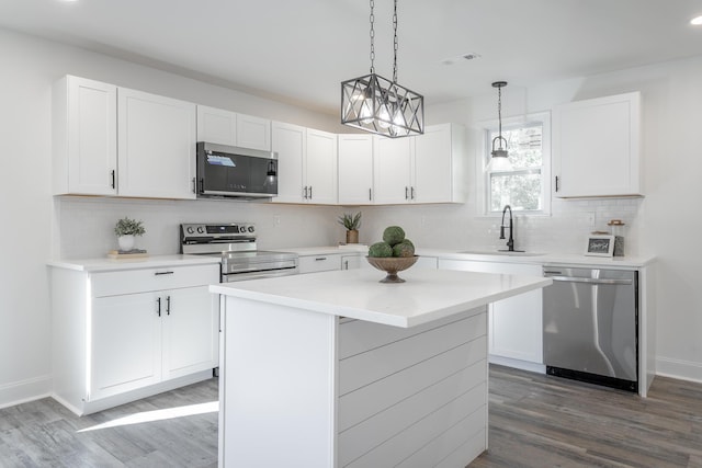 kitchen with sink, a kitchen island, white cabinets, and appliances with stainless steel finishes