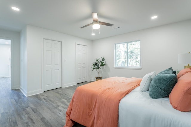 bedroom featuring two closets, light hardwood / wood-style flooring, and ceiling fan