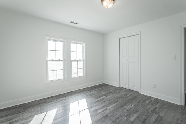 unfurnished bedroom featuring dark hardwood / wood-style flooring and a closet