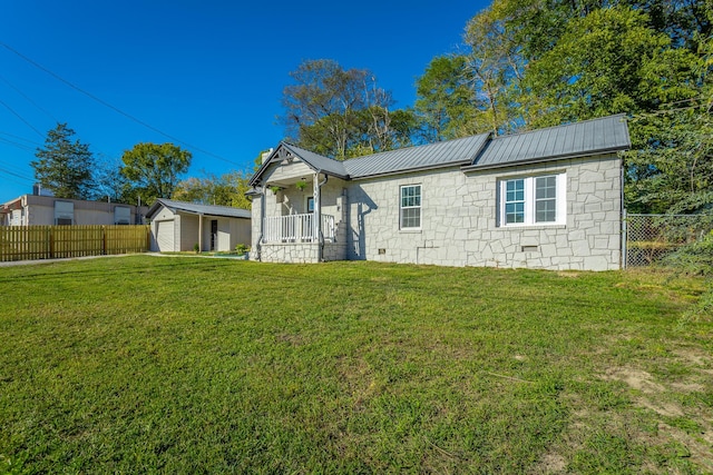 rear view of property with a garage, an outdoor structure, a porch, and a lawn