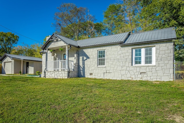 view of front of house with an outbuilding, a garage, a front yard, and covered porch