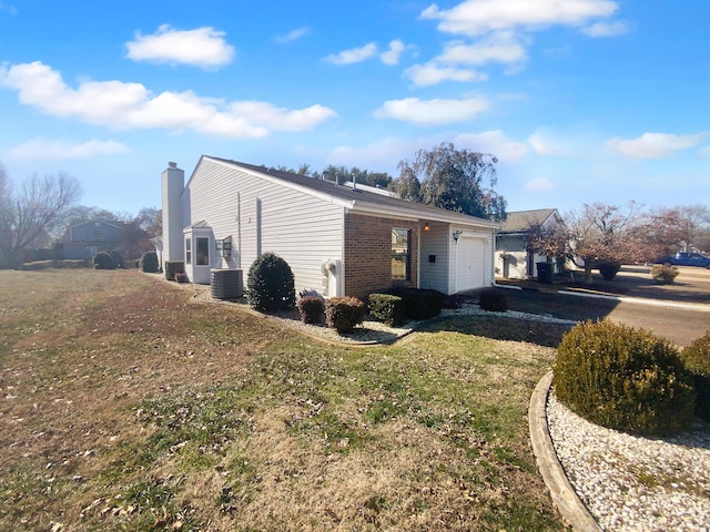 view of side of property featuring a garage, cooling unit, and a lawn