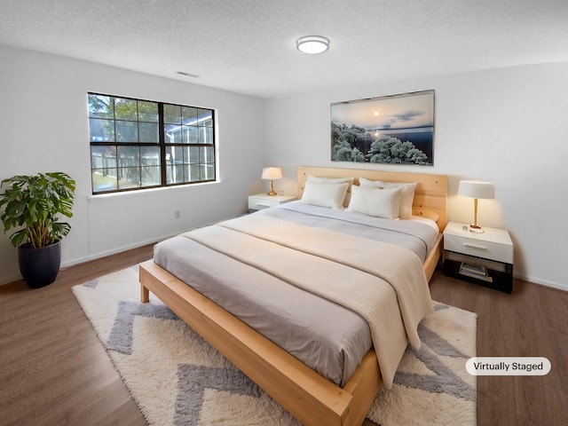 bedroom with dark hardwood / wood-style flooring and a textured ceiling