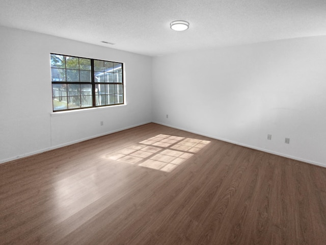 spare room featuring dark hardwood / wood-style floors and a textured ceiling