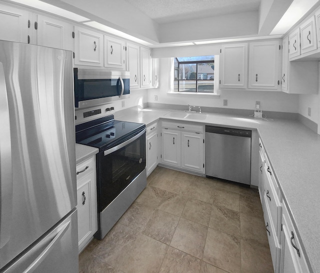 kitchen featuring stainless steel appliances, sink, a textured ceiling, and white cabinets