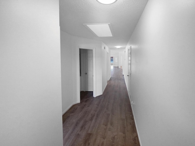 corridor with dark hardwood / wood-style floors and a textured ceiling