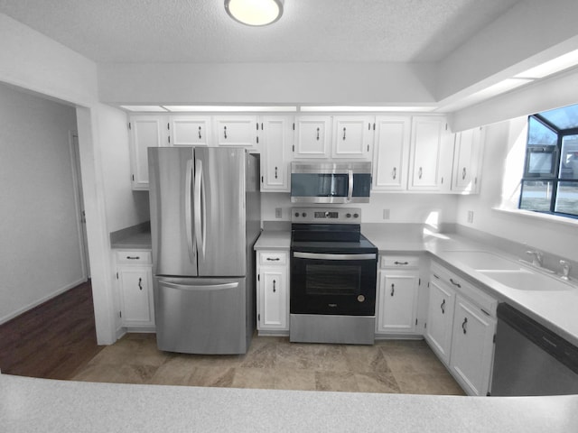 kitchen featuring stainless steel appliances, sink, a textured ceiling, and white cabinets