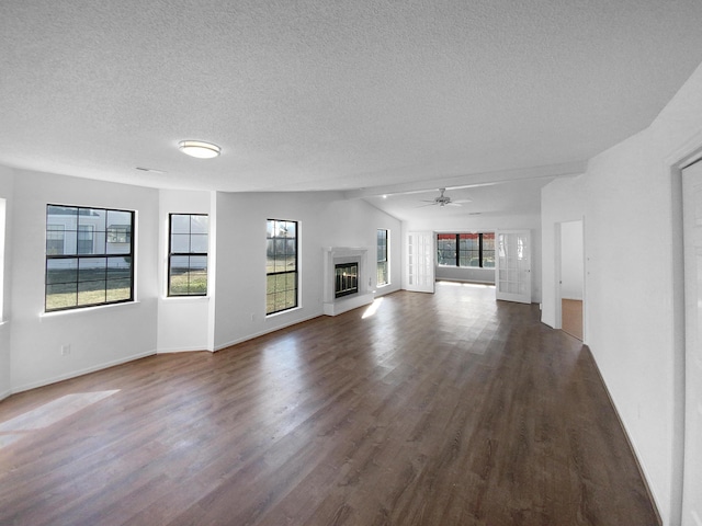 unfurnished living room with dark wood-type flooring, plenty of natural light, and ceiling fan