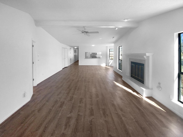 unfurnished living room with ceiling fan, lofted ceiling with beams, dark hardwood / wood-style floors, and a textured ceiling