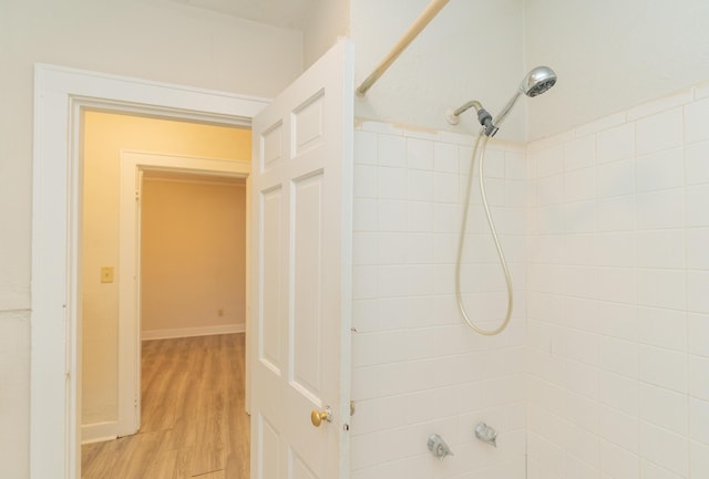 bathroom featuring wood-type flooring and tiled shower / bath