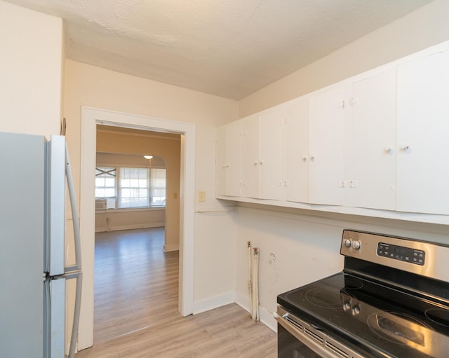 kitchen with electric range, light hardwood / wood-style flooring, white cabinets, and white refrigerator