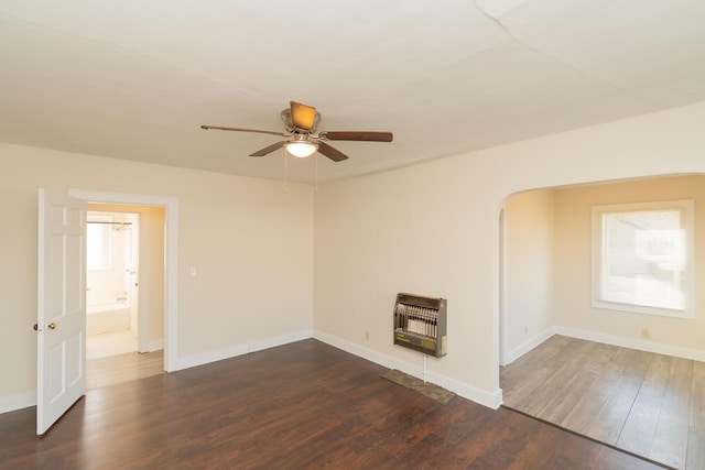 spare room with dark wood-type flooring, ceiling fan, and heating unit