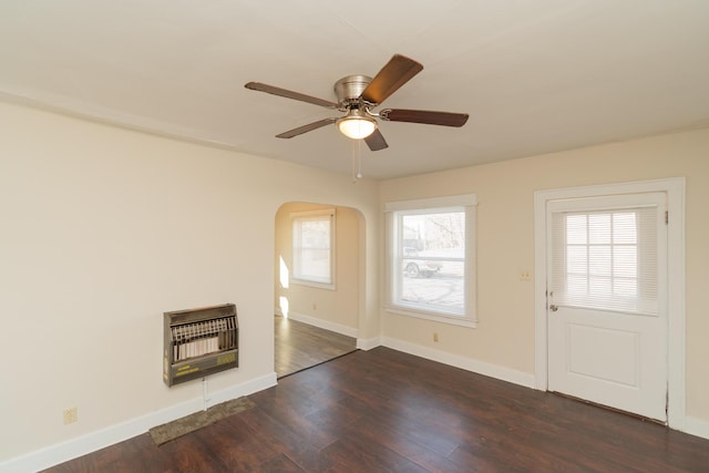 unfurnished living room with dark hardwood / wood-style floors, heating unit, and ceiling fan